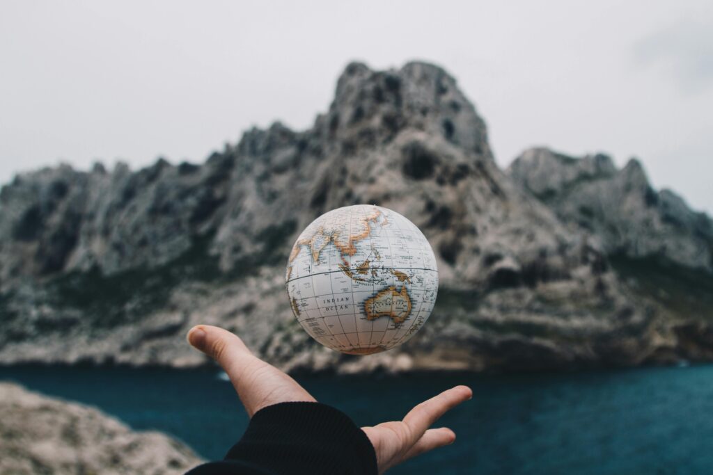 A hand holding a floating globe with a scenic Marseille backdrop, capturing adventure and exploration.